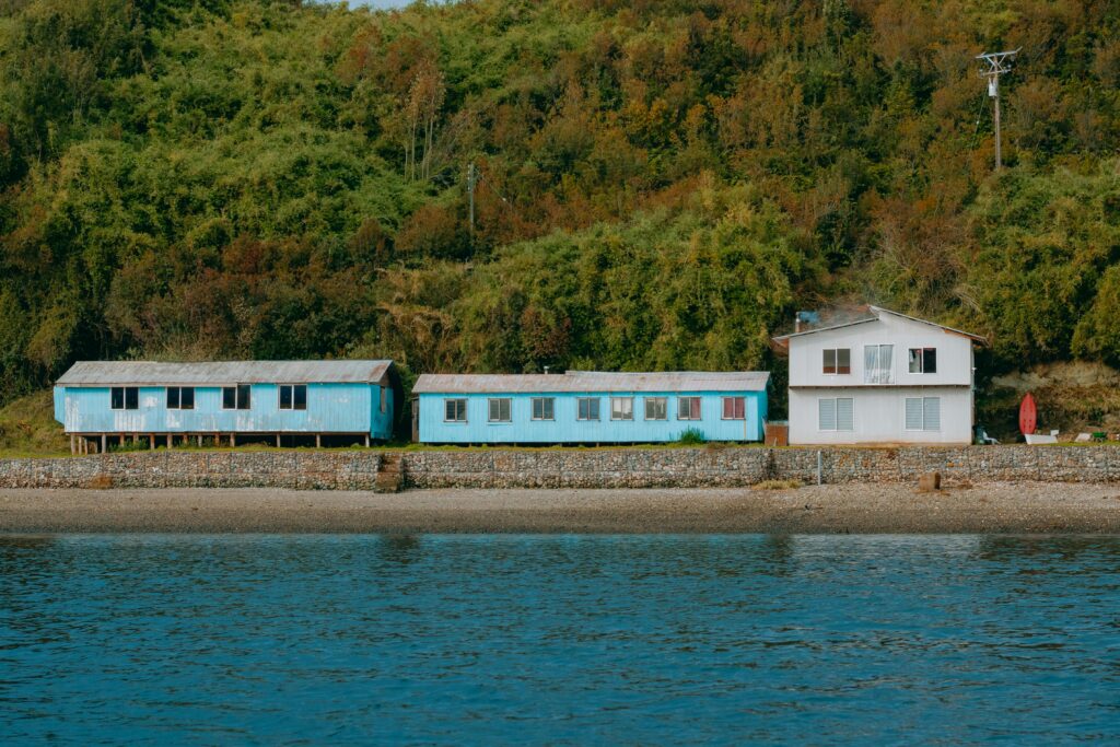 Colorful houses by the water in Puerto Montt, Chile, set against lush greenery.
